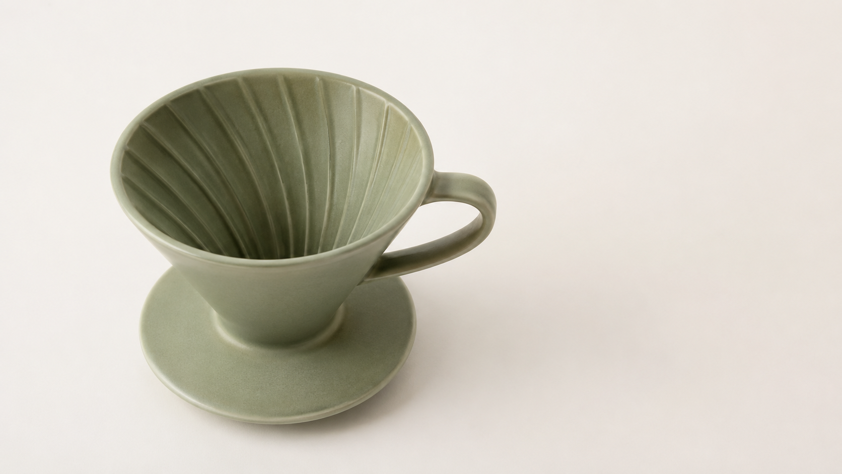 Sage green ceramic pour-over dripper on an off-white studio backdrop