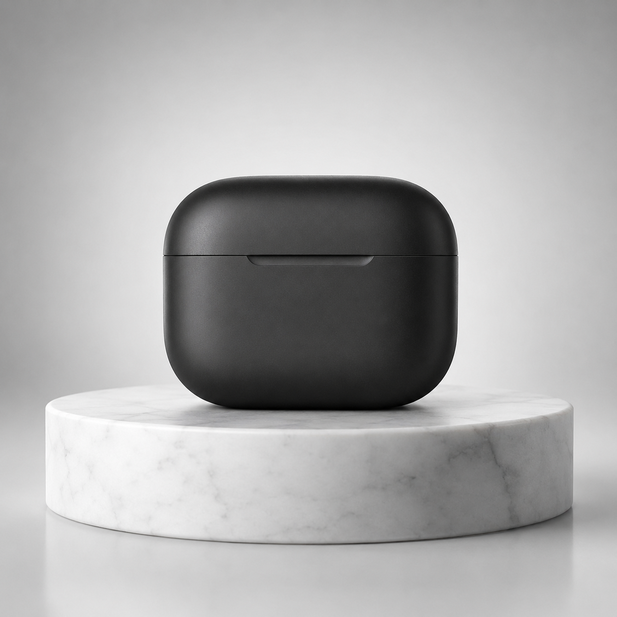 Matte black wireless earbuds charging case, closed, on a white marble pedestal against a gray gradient background