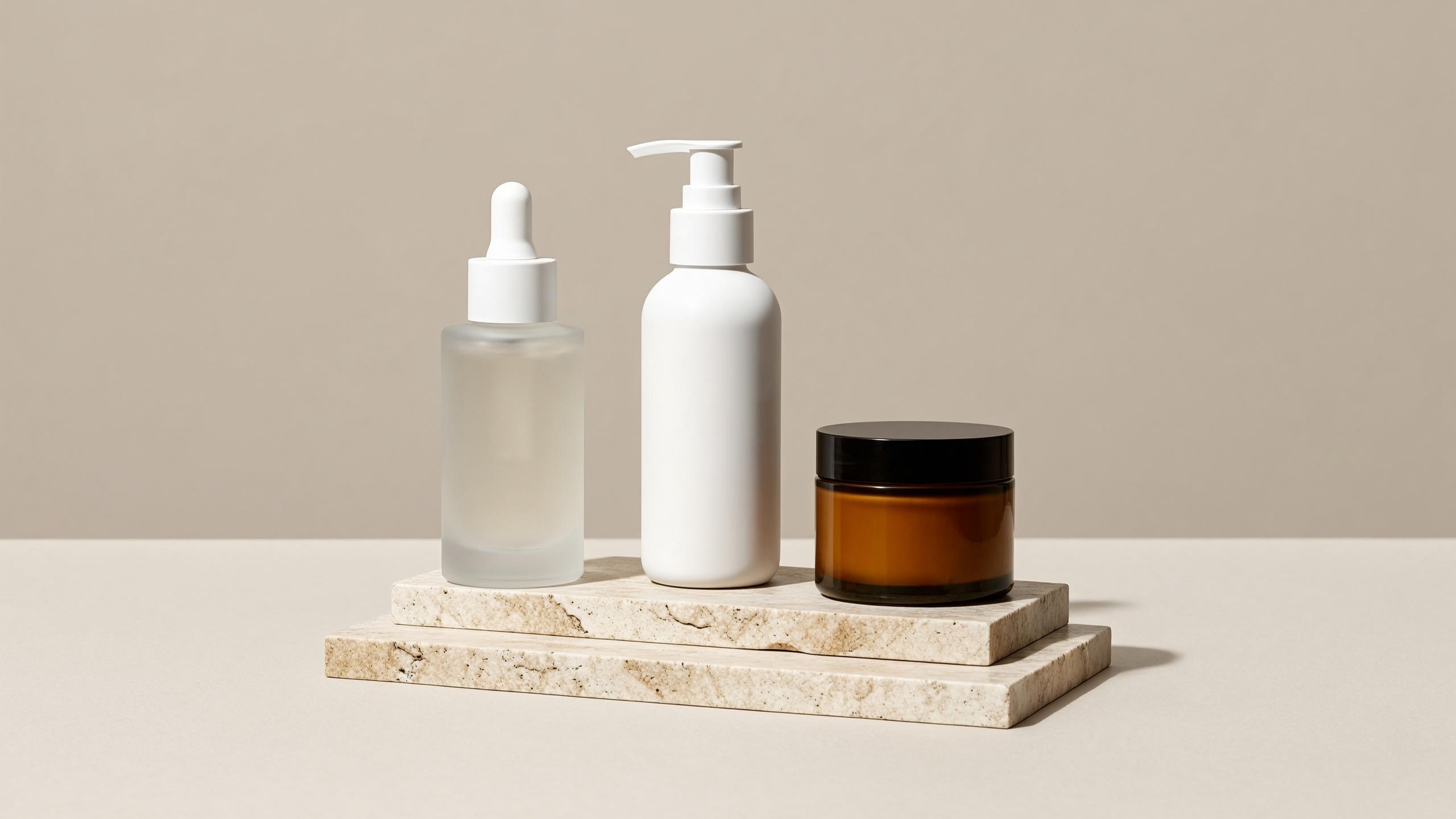 Three unlabeled skincare containers on a stone display podium, studio-lit e-commerce banner shot