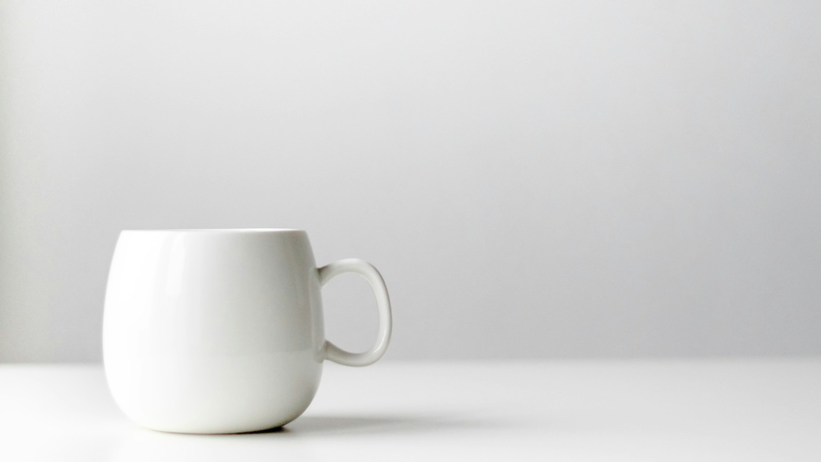 Source: a white ceramic mug on a white table in front of a plain white wall